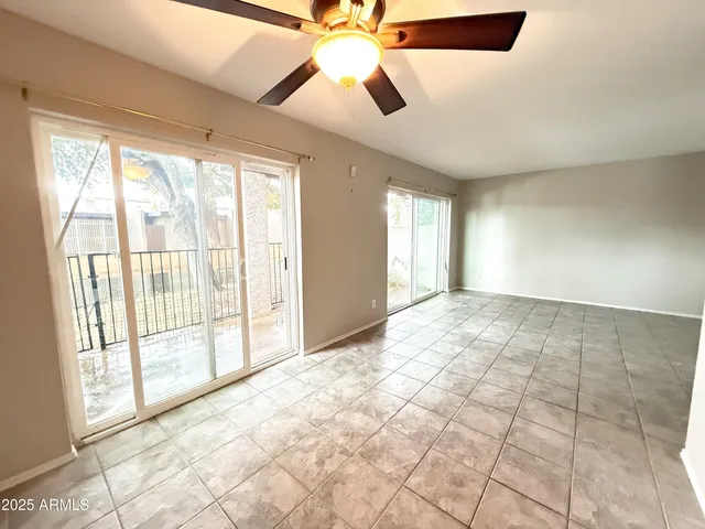 a view of an empty room and window and a chandelier fan