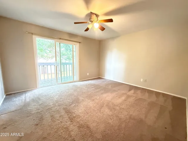 an empty room with windows and chandelier fan