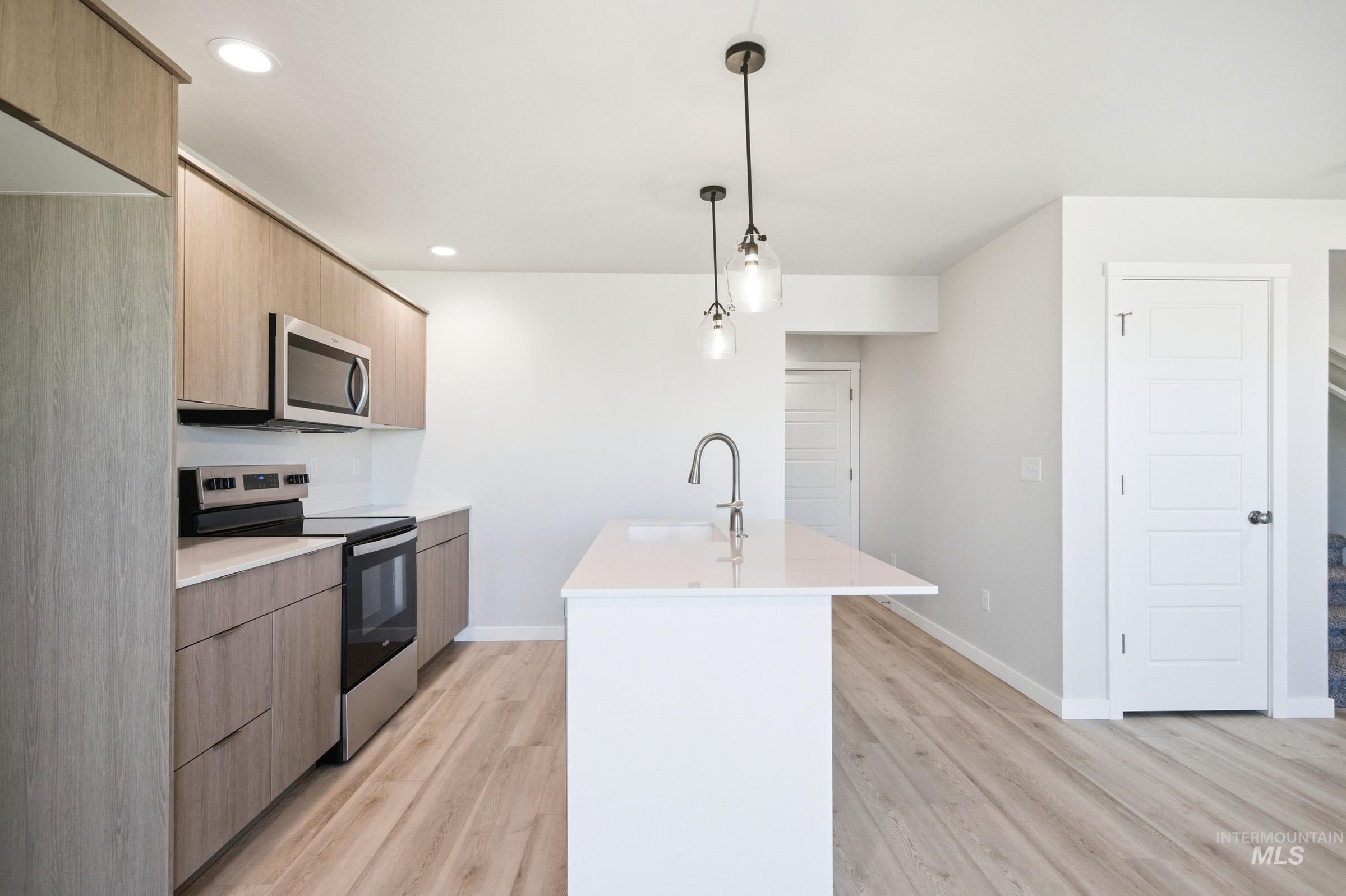 10800 Rutland Street Caldwell, ID 83605 - Photo 7 of 21 Kitchen featuring a central island with a gooseneck faucet, light wood-finish cabinetry, stainless steel appliances, recessed lighting, and pendant lighting