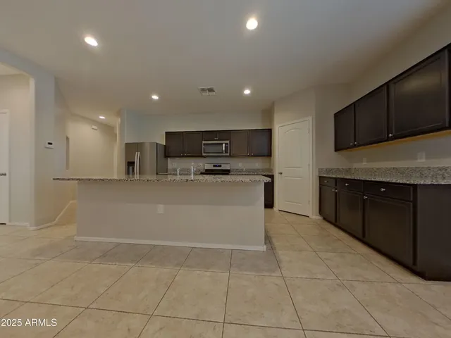 a view of open kitchen with stainless steel appliances a refrigerator and a microwave
