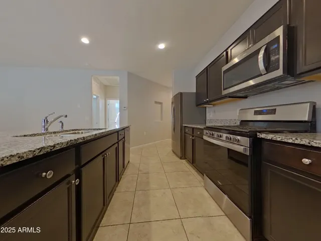 a large kitchen with stainless steel appliances granite countertop a stove a sink and a microwave