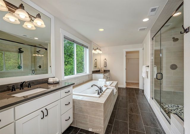 a bathroom with a double vanity sink a large mirror and a bathtub with shower