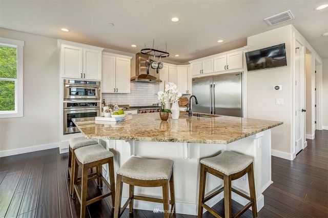 a kitchen with kitchen island granite countertop a table chairs microwave and cabinets