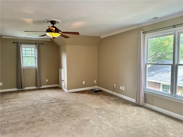 a view of an empty room with window and chandelier fan