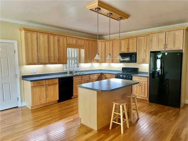 a kitchen with stainless steel appliances granite countertop a refrigerator a sink dishwasher a stove and a dining table with wooden floor