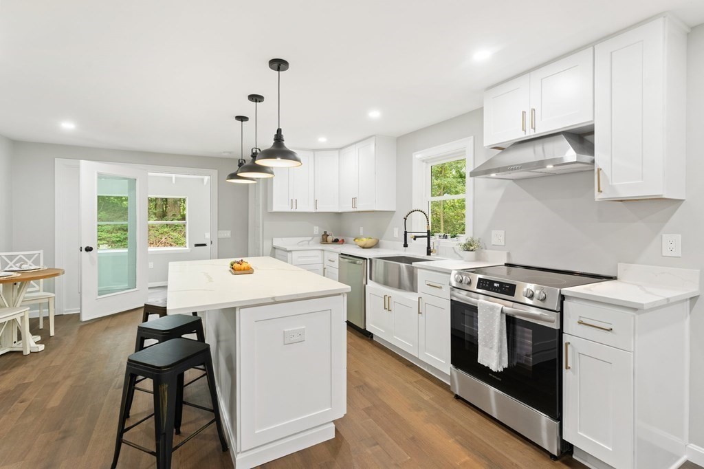 16 Chamberlain Road Shrewsbury, MA 01545 - Photo 11 of 38 a kitchen with granite countertop a stove a sink dishwasher and white cabinets with wooden floor