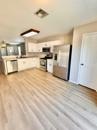 a kitchen with stainless steel appliances a stove a sink a microwave a refrigerator a counter space and cabinets