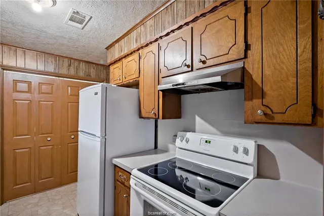 a kitchen with stainless steel appliances granite countertop a refrigerator a stove and a sink with wooden cabinets