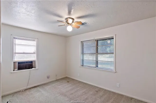 an empty room with windows and ceiling fan