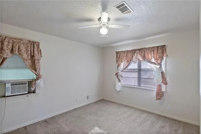 an empty room with windows and fan
