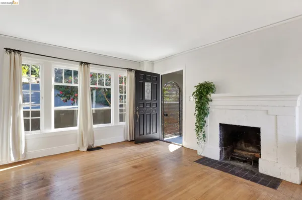 a view of an empty room with wooden floor and a fireplace