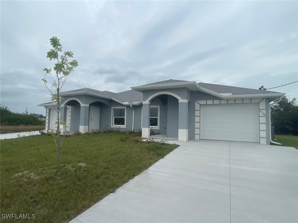 4524-4526 15th Street Southwest Lehigh Acres, FL 33973 - Photo 2 of 27 a front view of a house with a garden and yard