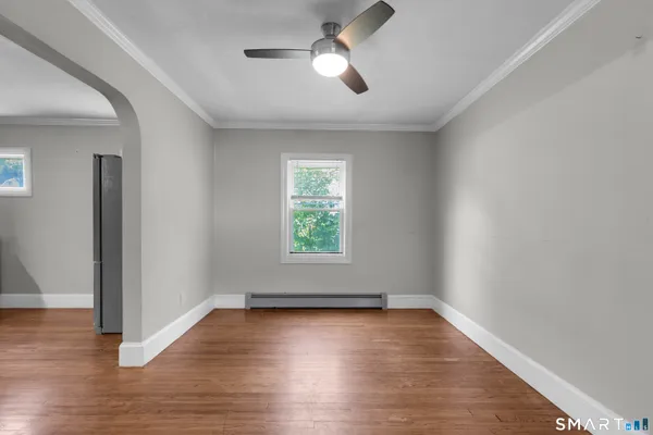 an empty room with wooden floor chandelier fan and windows