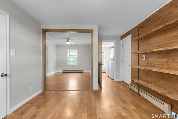 a view of a hallway with wooden floor and a bathroom