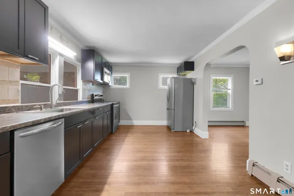 a large kitchen with stainless steel appliances granite countertop a large counter top a sink and a refrigerator