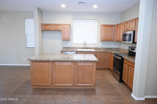 a kitchen with stainless steel appliances granite countertop a sink a stove a refrigerator dining table and chairs