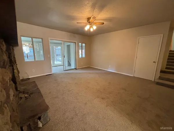 an empty room with windows and ceiling fan