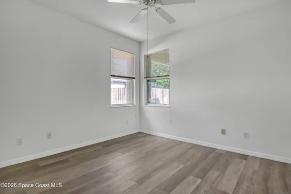 an empty room with a ceiling fan and window