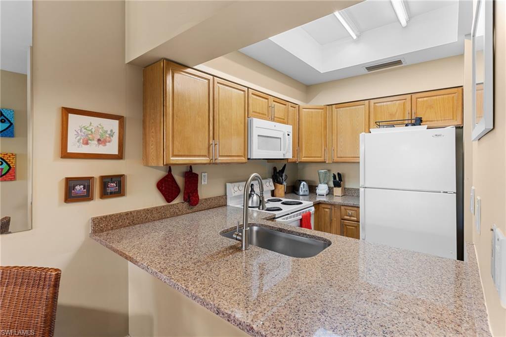 3324 Olympic Drive, Unit 313 Naples, FL 34105 - Photo 11 of 43 a kitchen with stainless steel appliances granite countertop a sink refrigerator and microwave