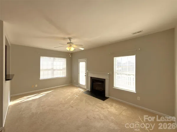 an empty room with windows and fireplace