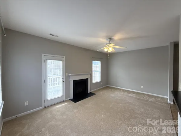 an empty room with a fireplace and chandelier fan