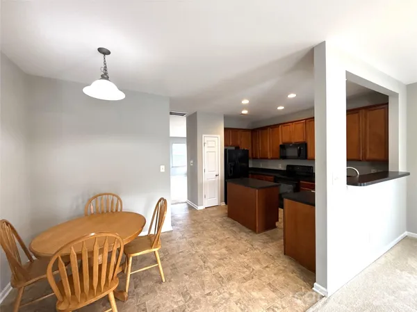 a kitchen with a dining table chairs and refrigerator