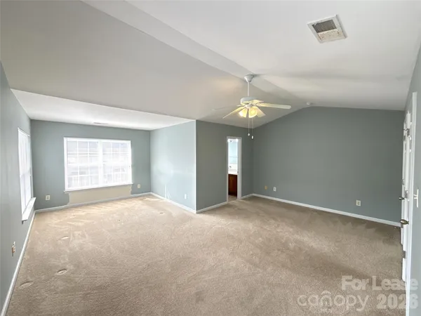 a view of an empty room with window and chandelier fan