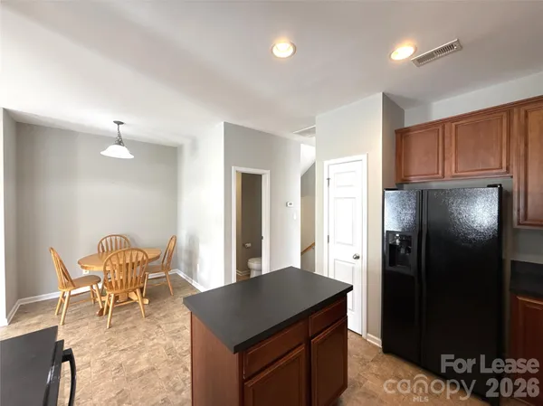 a kitchen with stainless steel appliances granite countertop dining table chairs and a refrigerator