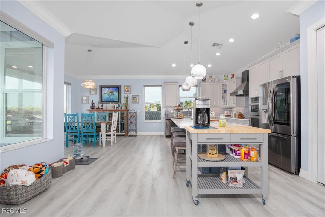 8425 Lagoon Road Fort Myers Beach, FL 33931 - Photo 8 of 49 a kitchen with stainless steel appliances granite countertop a refrigerator oven a stove top oven and a dining table with wooden floor