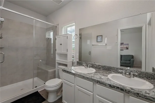 a bathroom with a granite countertop sink toilet and shower