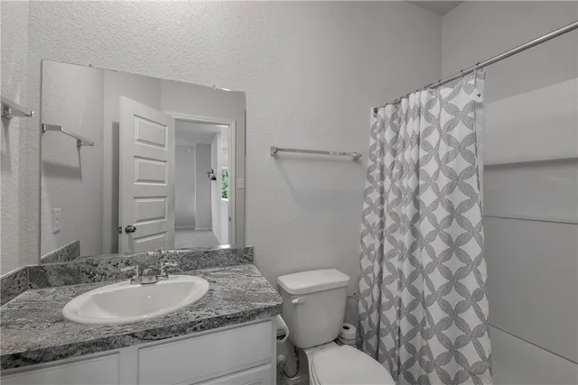 a bathroom with a granite countertop sink toilet and a mirror