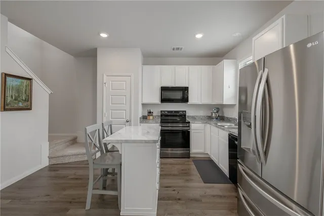 a kitchen with a refrigerator a microwave oven a sink dishwasher and white cabinets with wooden floor