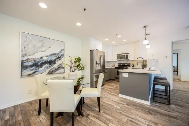 a living room with stainless steel appliances furniture a dining table and kitchen view