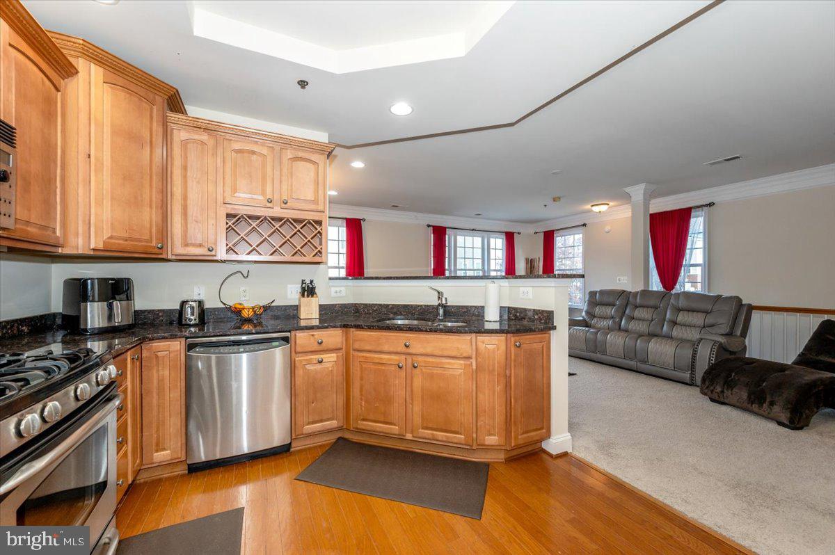 3541 Huntley Manor Lane, Unit 79B Alexandria, VA 22306 - Photo 13 of 40 a kitchen with stainless steel appliances granite countertop a stove top oven a sink dishwasher and cabinets with wooden floor