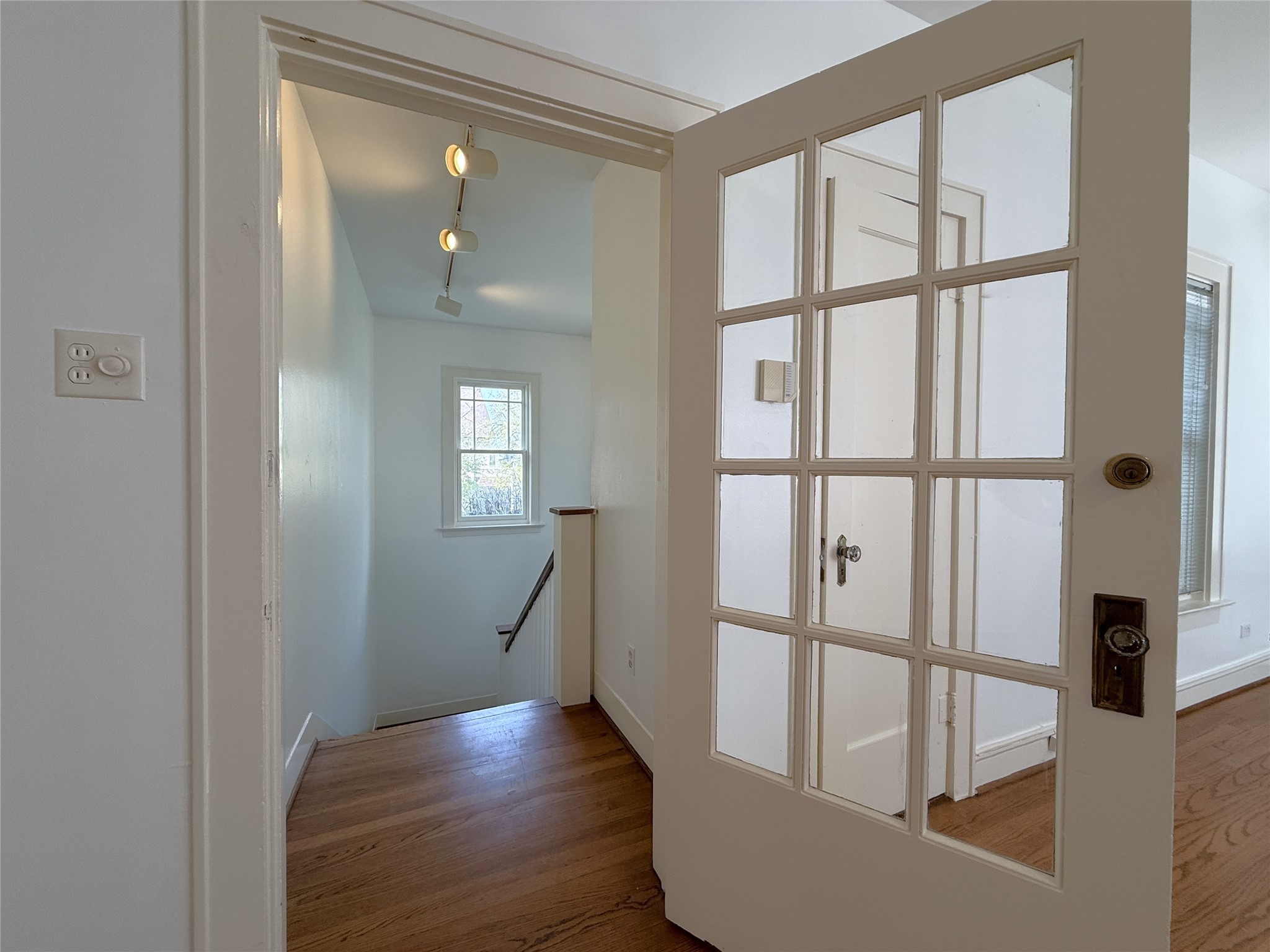 2311 Wroxton Road Houston, TX 77005 - Photo 4 of 24 A glass paned door opens into the living room. Notice the tract lighting above the stairs.