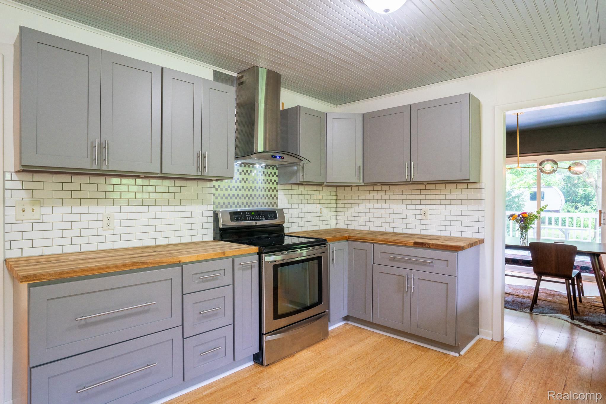 7333 Toma Road Dexter, MI 48130 - Photo 24 of 45 Kitchen featuring gray shaker-style cabinetry, wood-finish countertops, stainless steel appliances, and a subway tile backsplash