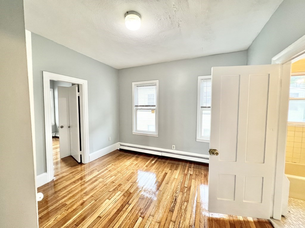 113 Ferry Street, Unit 2 Everett, MA 02149 - Photo 4 of 6 a view of an empty room with wooden floor and a window