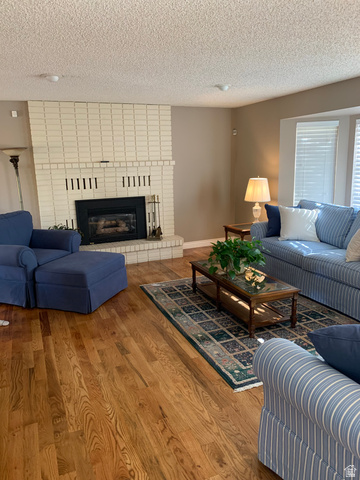 220 West Mill Road Ferron, UT 84523 - Photo 12 of 40 Living area featuring wood-finish flooring, a white brick fireplace, a built-in fireplace insert, and window blinds