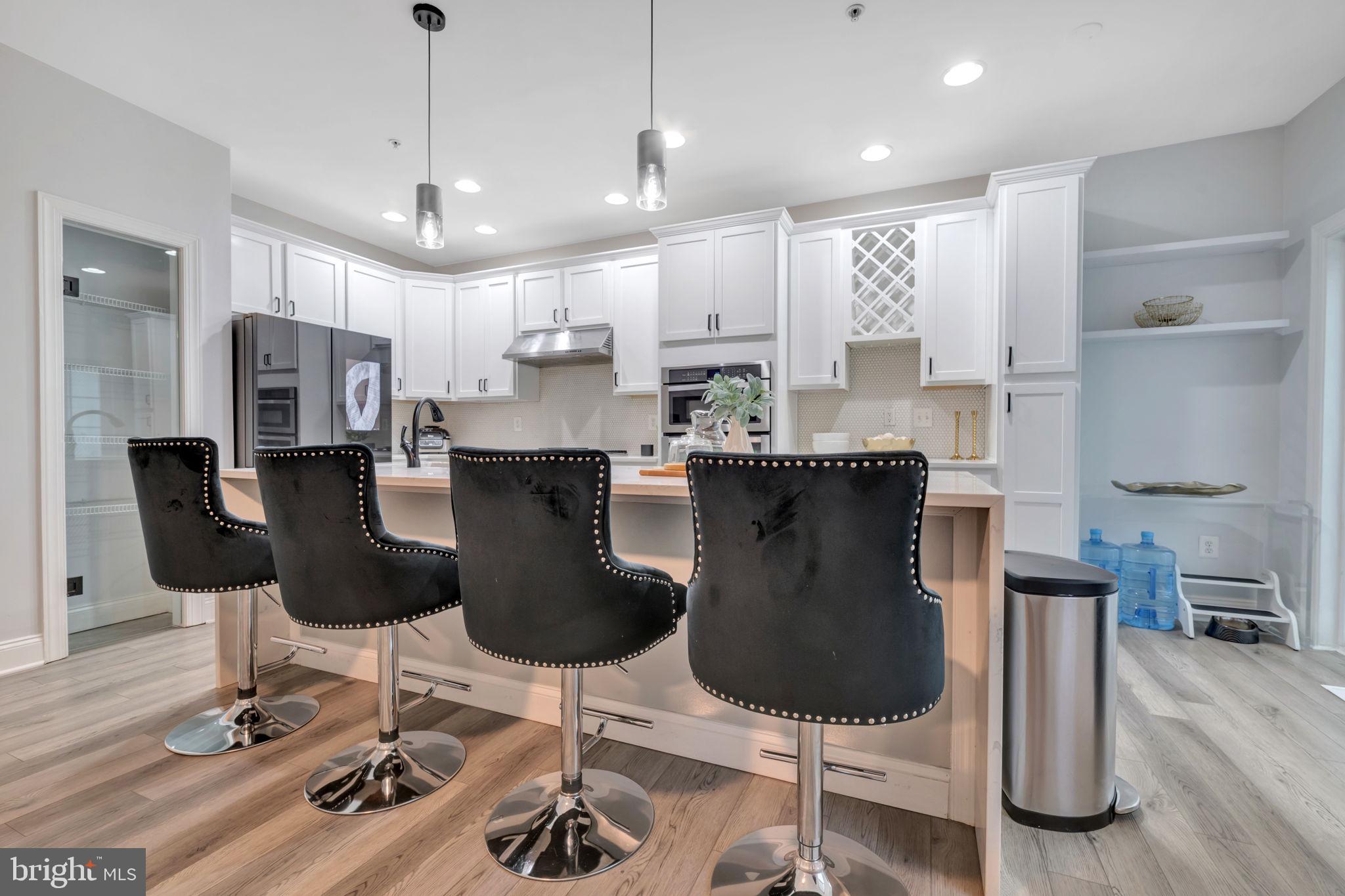 7619 Elmcrest Road Hanover, MD 21076 - Photo 4 of 35 a kitchen with stainless steel appliances kitchen island granite countertop a dining table chairs and a refrigerator