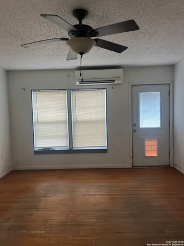 a view of an empty room with a window and wooden floor