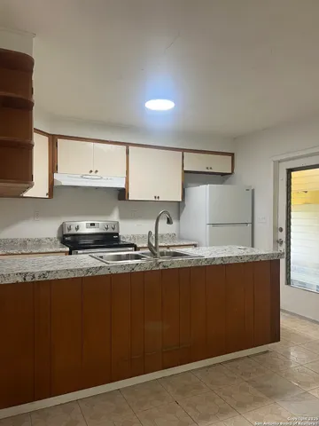 a kitchen with granite countertop a sink a stove and cabinets
