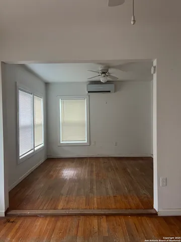 an empty room with wooden floor cabinet and windows