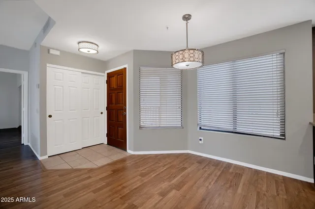 a view of an empty room with wooden floor and windows