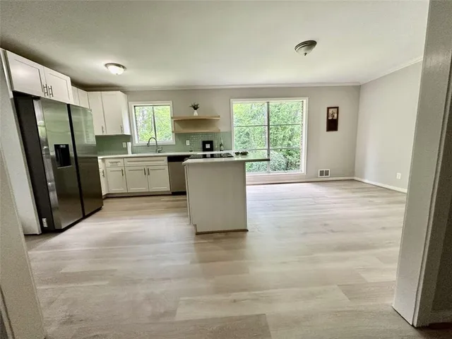 a large white kitchen with a window and refrigerator