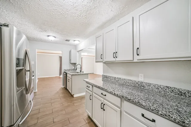 a kitchen with granite countertop white cabinets and stainless steel appliances
