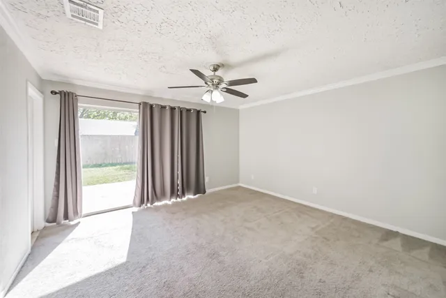 an empty room with window and a ceiling fan