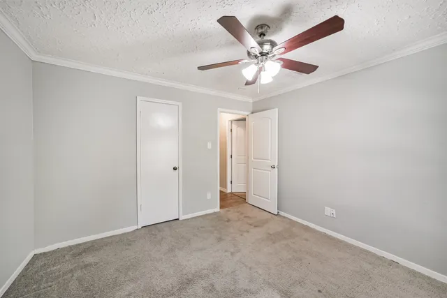 an empty room with closet and view of a ceiling fan