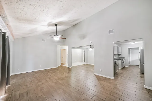 a view of a livingroom with a ceiling fan wooden floor and a ceiling fan