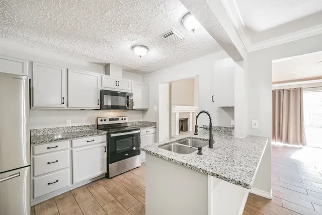 a kitchen with granite countertop a sink stainless steel appliances and white cabinets