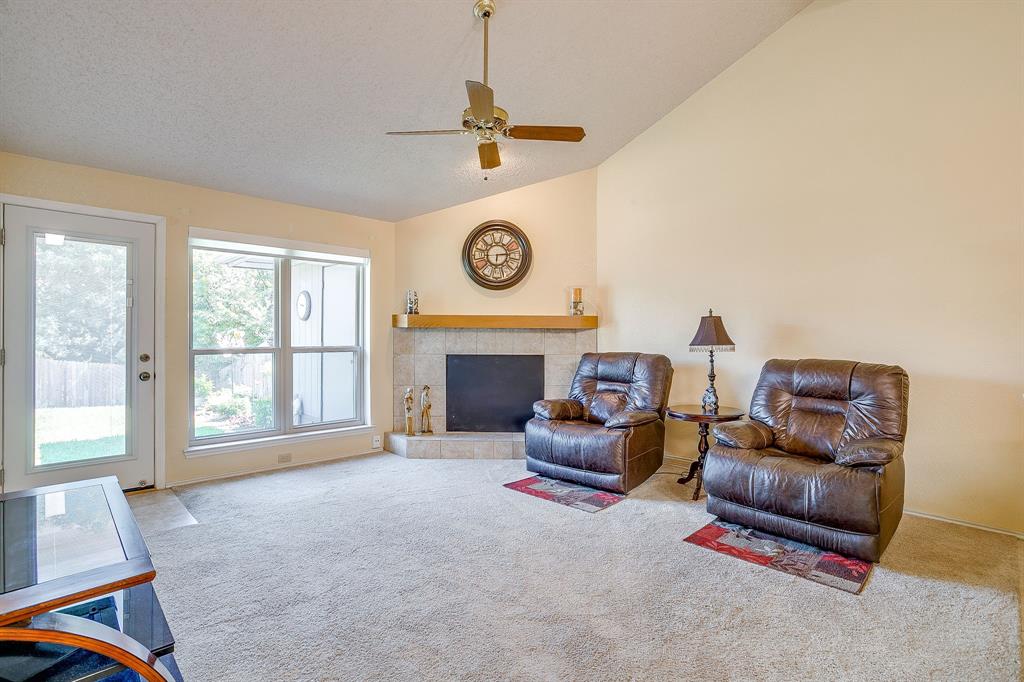 1116 Highpoint Road Bedford, TX 76022 - Photo 7 of 37 Carpeted living room featuring a fireplace, a ceiling fan, a textured ceiling, and high vaulted ceiling